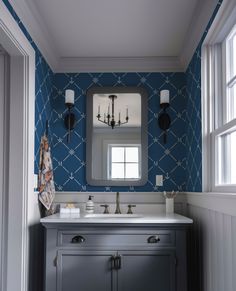 a bathroom with blue and white wallpaper and a large mirror above the vanity area