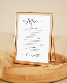 a menu card sitting on top of a wooden plate next to a feathery object