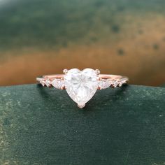 a heart shaped diamond ring sitting on top of a green surface