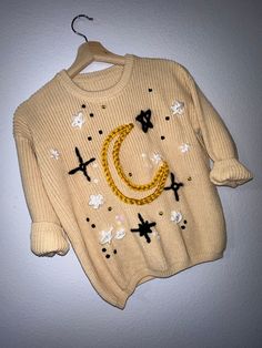 a sweater hanging on the wall with a cross and crescent design painted on it's front