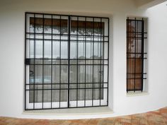 an empty room with two windows and some bars on the window sill in front of it