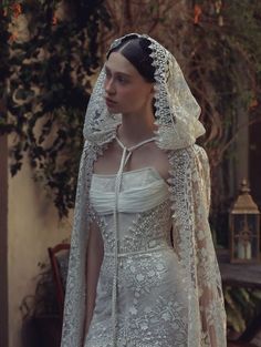 a woman in a white wedding dress with a veil on her head and long sleeves