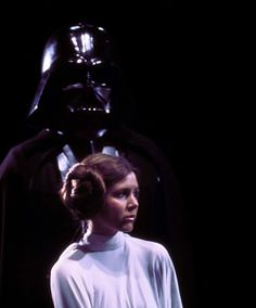 a woman standing next to a darth vader