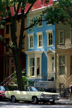 two cars are parked on the street in front of colorful houses