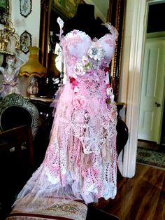 a dress made out of lace and flowers on display in a room with other items