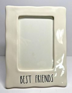 a white photo frame with the words best friends written on it in black ink, sitting on a table