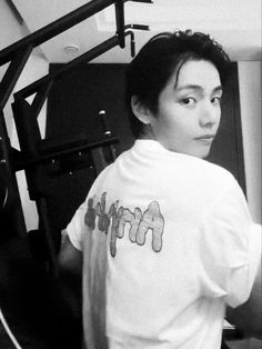 a young man standing in front of a gym equipment rack and looking at the camera