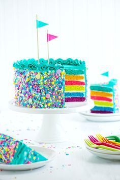 there is a colorful cake with sprinkles on it and two plates next to it