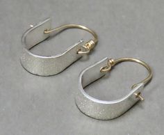 These are not your ordinary hoop earrings:   4mm distressed pattern 18 gauge sterling sheet forms the base of this earring.   It's 1/2 inch wide and 1 inches in length, and has a hand forged sturdy 19 gauge gold filled ear wire that secures into a drilled hole.  Simple design but sleek, contemporary statement.   Please allow 10 days for fabrication. Returns: Customer service is of the utmost importance to me.  If you're not completely satisfied with your purchase, I accept returns within 2 weeks Small Hammered Metal Hoop Earrings, Small Hoop Metal Wrap Earrings, Silver Brass Small Hoop Huggie Earrings, Minimalist Hammered Metal Hoop Earrings, Handmade Minimalist Small Hoop Wrap Earrings, Adjustable Soldered Hoop Earrings For Gifts, Everyday Silver Hoop Earrings With French Hook, Unique Small Hoop Jewelry With Ear Wire, Artisan Small Hoop Sterling Silver Earrings