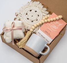 an open box containing a coffee mug, tassels and other items