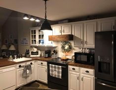 a kitchen with white cabinets, black appliances and wood counter tops is shown in this image