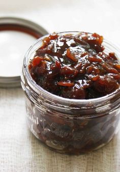 a glass jar filled with raisins sitting on top of a white table cloth