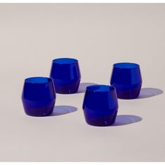 four blue glass cups sitting next to each other