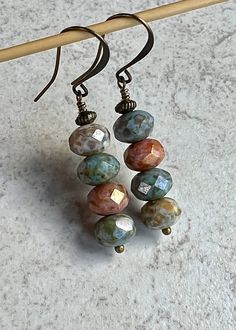 "multi color boho dangle earrings   czech glass stack earrings Four faceted Czech glass beads are stacked together along with a tiny antiqued brass bead sitting at the top. The colors are blue, ivory and pinky-orange, all with a heavy picasso coating. Hook ear wires are antiqued brass. Length of earrings from top of ear wires is 2\". Glass beads measure 5x8mm. You can enter my shop here: gypsydangles.etsy.com" Boho Earrings Diy Handmade Jewelry, Czech Glass Bead Earrings, Czech Glass Drop Earrings, Dyi Earrings, Czech Beads Jewelry, Stack Earrings, Pinky Orange, 2024 Jewelry, Earrings Handmade Boho