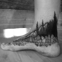 a black and white photo of a person's foot with trees on it