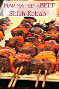 meat and vegetable kabobs on skewers with text overlay that reads marinated beef shish kebab