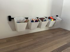 three white bins with pencils and crayons in them on a wall