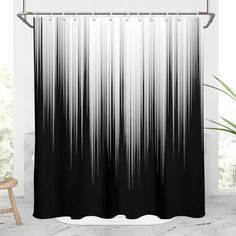 a black and white shower curtain hanging on a wall next to a chair in front of a window