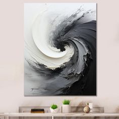 a white and black abstract painting on a wall in a living room with a table