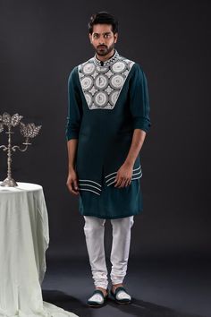 Peacock green sleeveless asymmetric bundi with bloom embroidery using pearls and beads. Paired with long sleeves plain kurta and matching churidar.
Components: 3
Pattern: Embroidered
Type Of Work: Pearl Bloom
Neckline: Band Collar
Sleeve Type: Bundi: Sleeveless, Kurta: Long
Fabric: Mal Cotton, Moss Crepe, Cotton Lycra
Color: Green
Other Details: 
Approx weight: 2kgs
Poly lining
Occasion: Mehendi and Puja, Sangeet - Aza Fashions Designer Sleeveless Kurta For Eid, Green Sleeveless Kurta With Resham Embroidery, Green Sleeveless Resham Embroidered Kurta, Designer Sleeveless Kurta For Transitional Season, Green Sleeveless Embroidered Traditional Wear, Sleeveless Kurta With Dabka Work For Eid, Sleeveless Kurta With Intricate Embroidery For Eid, Festive Sleeveless Kurta With Dabka Work, Green Sleeveless Kurta For Diwali