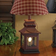 a lamp that is on top of a wooden table next to a potted plant