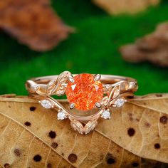 an orange diamond ring sitting on top of a leaf