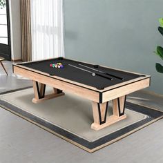 a pool table in the middle of a room with a potted plant on the floor