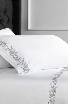 a bed with white sheets and pillows on top of it