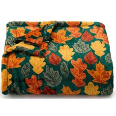 a green blanket with orange and yellow leaves on the bottom is folded up to show it's fall colors