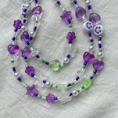 "Cute purple-green necklace made from a mix of beads in the shape of stars, flowers, butterflies and pearls💜💚Stainless steel clasp.  ♡IMPORTANT: - Listing is for 1 necklace - Video without filters  ♡SIZE: - This necklace is made in 15.7\" length or 40 centimeters (adjustable) - The size of the choker is standard, but if you need a specific size, write it in the notes to the order or in a message. ♡GIFT - Gift for buying 2 or more items in our store ♡SHIPPING - We send from Bulgaria - We ship all orders with a track number and do expedited shipping, but due to the pandemic, orders delivery may still take longer time - Your item will be dispatched within 3 working days - Please see our shop policies for full details ♡COLORS: - Colors may vary due to filters, you can watch a video with natu Green Heart-shaped Beaded Necklace, Green And Purple Aesthetic, Necklace Video, Smiley Beads, 2000s Indie, Green Y2k, Kidcore Aesthetic, Rave Accessories, Butterfly Heart