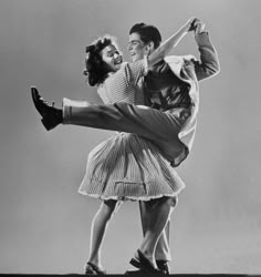 an old photo of two people doing ballet moves in front of a gray background with the caption's name on it