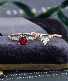 a red stone ring sitting on top of a velvet case next to other jewelry items