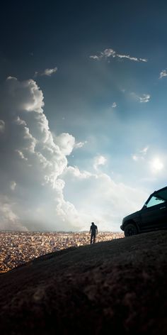 a car parked on top of a hill next to a person standing in the distance