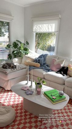 a living room filled with furniture and a cat laying on top of a table next to a window