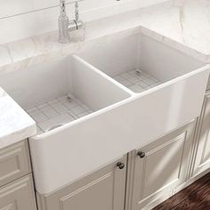 two white sinks in a kitchen with marble counter tops