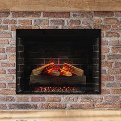 a brick fireplace with logs burning in it