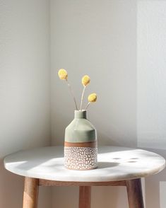 a small vase with three yellow flowers in it sitting on a table next to a window