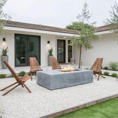 an outdoor fire pit in the middle of a yard with lawn chairs and potted trees