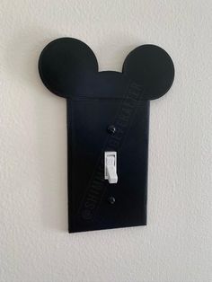 the mickey mouse light switch cover is black and has a white face on it's side