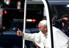 the pope gives thumbs up as he rides in a car with another man behind him