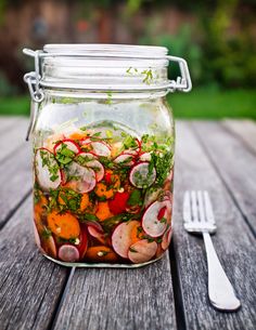 a mason jar filled with sliced radishes and other veggies next to a fork