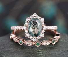 an engagement ring with a green stone surrounded by white and rose gold diamond halos