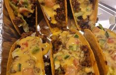 some taco shells are sitting on a tray with cheese and other toppings in them