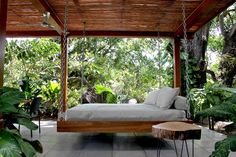 a bed sitting in the middle of a lush green forest next to a wooden platform