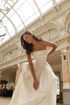 a woman in a white wedding dress is posing for the camera