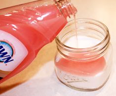 a glass jar filled with liquid sitting on top of a table next to a bottle