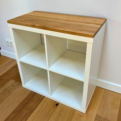 a white bookcase with wooden top and shelves