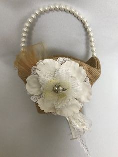 a white flower on a burlap bag with pearls and feathers attached to it