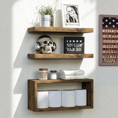 two wooden shelves with various items on them against a white wall in a bathroom area