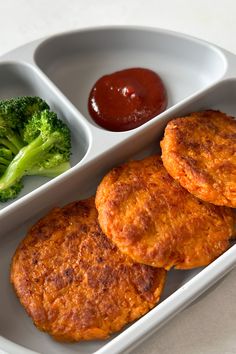 two pieces of fried food in a white tray with broccoli and ketchup